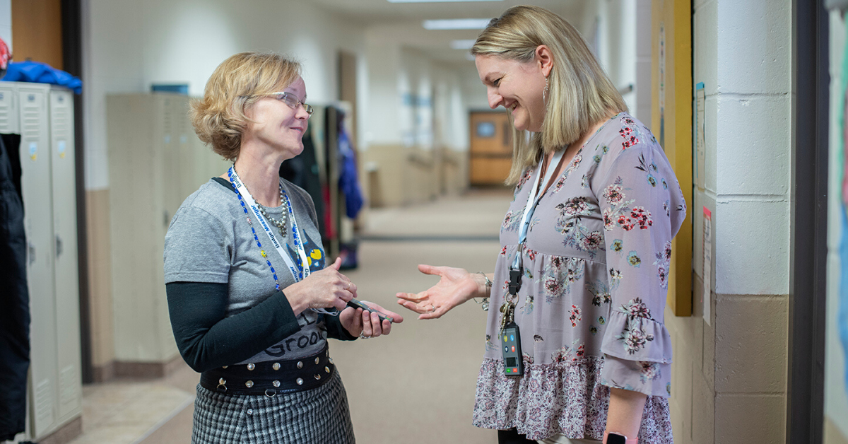two teachers discussing Badge Messenger® in the hall